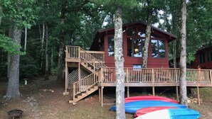 Une cabane dotée d’une terrasse en bois, d’un escalier et offrant une vue sur la forêt environnante.