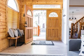 A wooden interior with a bench, a door leading outside, and a staircase.
