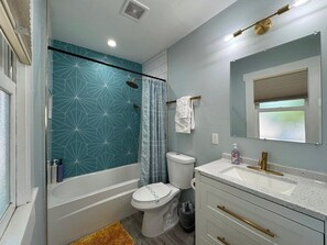 Een bad/douchecombinatie, een haardroger, handdoeken, zeep