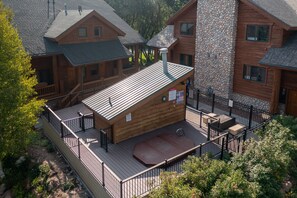 Eine Holzhütte mit einer Terrasse, einem Steinofen und einem umzäunten Patio.