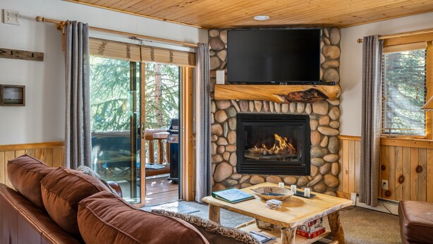 Ein gemütliches Wohnzimmer mit Kamin aus Naturstein, einem Flachbildfernseher und einer bequemen Sitzecke.