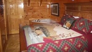 Quarto de cabana de madeira com cama, uma janela grande e teto de madeira.
