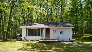 A small white cabin with a star decoration, a porch, and a sign that reads "Cottage." - Private Up North getaway - short walk to lake (Spruce)