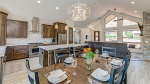 Una cocina moderna con armarios de madera oscura, una isla grande, electrodom ésticos de acero inoxidable e iluminación colgante.