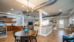 A spacious kitchen with wooden cabinets, a dining area with a round table, and a living area with a sofa.