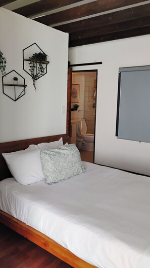 A bedroom with a wooden bed, white bedding, and geometric wall decorations. - Cozy, spacious off grid cabin. Perfect for 4 adults, or small family. (Joshua Tree)