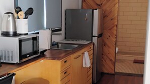 Cocina compacta con microondas, cafetera y un cubo de basura de acero inoxidable.
