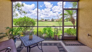 A room with a large sliding glass door leading to a grassy area, a small table with a potted plant, and a chair. - Beautiful 3Br/2.5Ba Golf Course Townhome w/Bunk Room for the Kids! (Lakewood Ranch)
