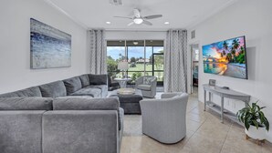 A modern living room with a grey sectional sofa, a grey armchair, and a TV on a console table. - Beautiful 3Br/2.5Ba Golf Course Townhome w/Bunk Room for the Kids! (Lakewood Ranch)