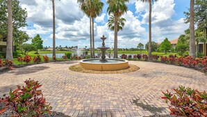 A circular brick pathway with a central fountain, surrounded by palm trees and landscaped gardens. - Beautiful 3Br/2.5Ba Golf Course Townhome w/Bunk Room for the Kids! (Lakewood Ranch)