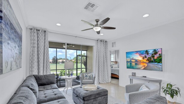 A modern living room with a grey sectional sofa, a grey armchair, a small round table, and a flat-screen TV mounted on the wall. - Beautiful 3Br/2.5Ba Golf Course Townhome w/Bunk Room for the Kids! (Lakewood Ranch)