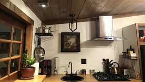 Eine Küche mit Holzbalkendecke, einem Gaskochfeld, einer Spüle und verschiedenen Küchenutensilien.