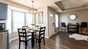 A dining area with a table set for four, a kitchen with a microwave, and a living area with two chairs and a coffee table. - Once-In-A-Lifetime Coffee-Themed Stay For Up To 8. (Clarksville)