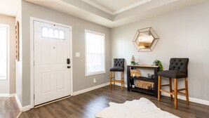 A room with a white door, two chairs, a small table, a mirror, and a rug. - Once-In-A-Lifetime Coffee-Themed Stay For Up To 8. (Clarksville)