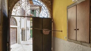 A doorway with a decorative metal arch, a basket hanging on the door, and a wooden cabinet to the right. - Canton Balin by Interhome (Meina)