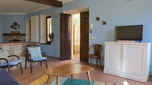 A living room with a stone fireplace, wooden furniture, a television on a cabinet, and a door leading outside. - Canton Balin by Interhome (Meina)