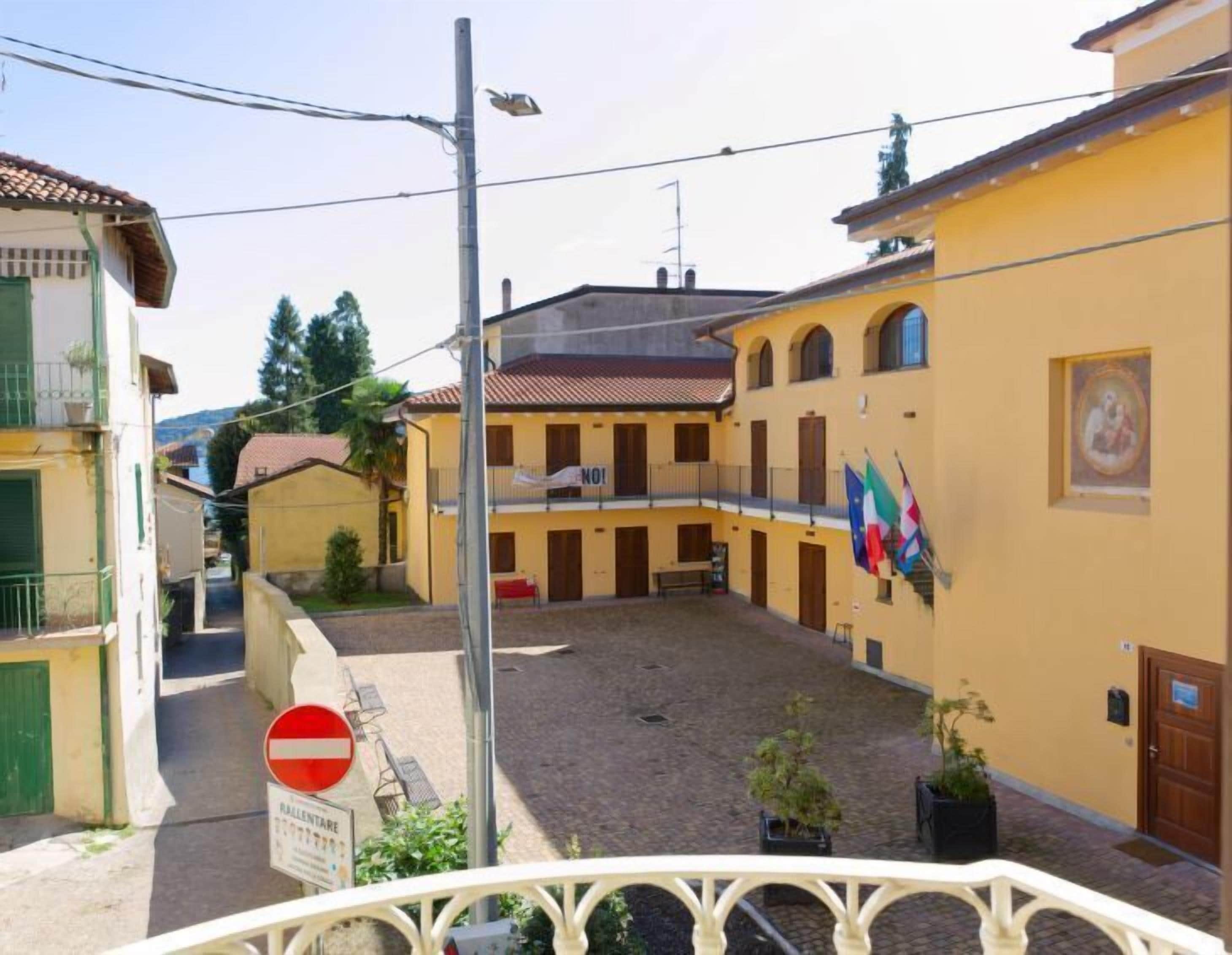 A courtyard with a building featuring a balcony, a 'no entry' sign, and a flag.