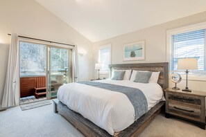 A bedroom with a large bed, a wooden bench, a nightstand, and a view of a snowy landscape through the window.