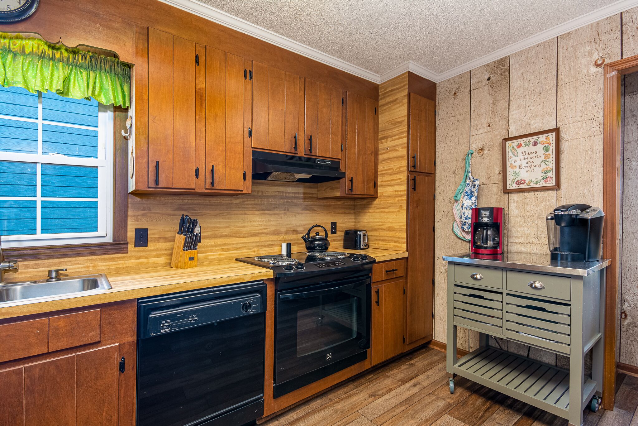 A kitchen with wooden cabinets, a dishwasher, an oven, and a coffee maker.