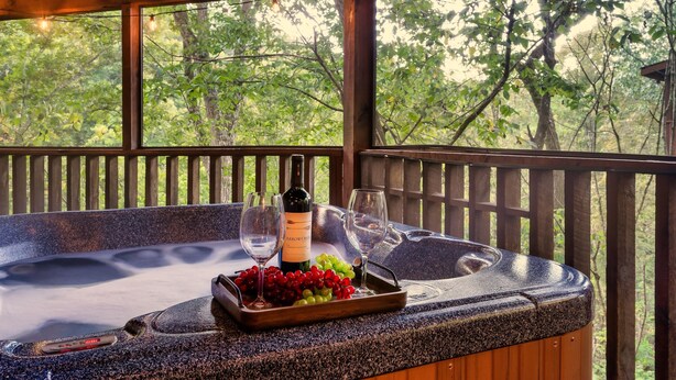 Ein Whirlpool mit einer Schale Trauben und einer Flasche Arrow Creek Wein, umgeben von einer Holzterrasse und Bäumen.