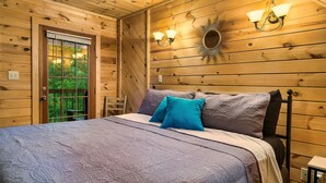 Ein Schlafzimmer mit Holzwänden, einem Bett, Kissen und Wandleuchten.