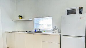A kitchen with a sink, a window, a microwave, and a refrigerator. - Boulevard 107 (Mayagüez)