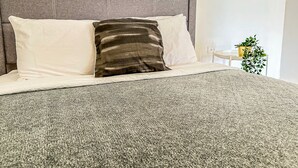 A bed with a grey headboard, white pillows, and a grey textured bedspread. - Boulevard 107 (Mayagüez)