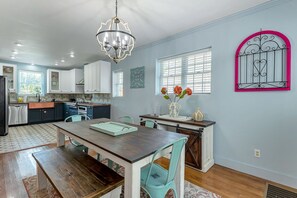 Une cuisine avec des meubles blancs, une table à manger en bois et des chaises de couleur turquoise.