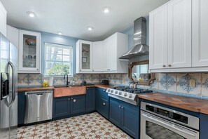 A kitchen with blue cabinets, a stainless steel stove, and a dishwasher.