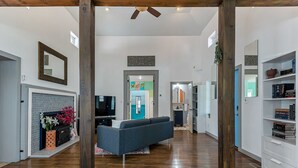 A spacious living area with a fireplace, a sofa, and a bookshelf. - Norfolk Beach Casita / Fenced Yard / Dog Friendly (Norfolk)