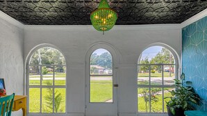 A room with a view through three arched windows, a patterned floor, and a green chandelier. - Norfolk Beach Casita / Fenced Yard / Dog Friendly (Norfolk)
