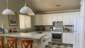 Una cocina con armarios blancos, una estufa de acero inoxidable y un suelo a cuadros.