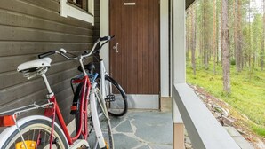 Un bâtiment en bois avec un porche, un vélo rouge et un vélo blanc garés à l’extérieur.