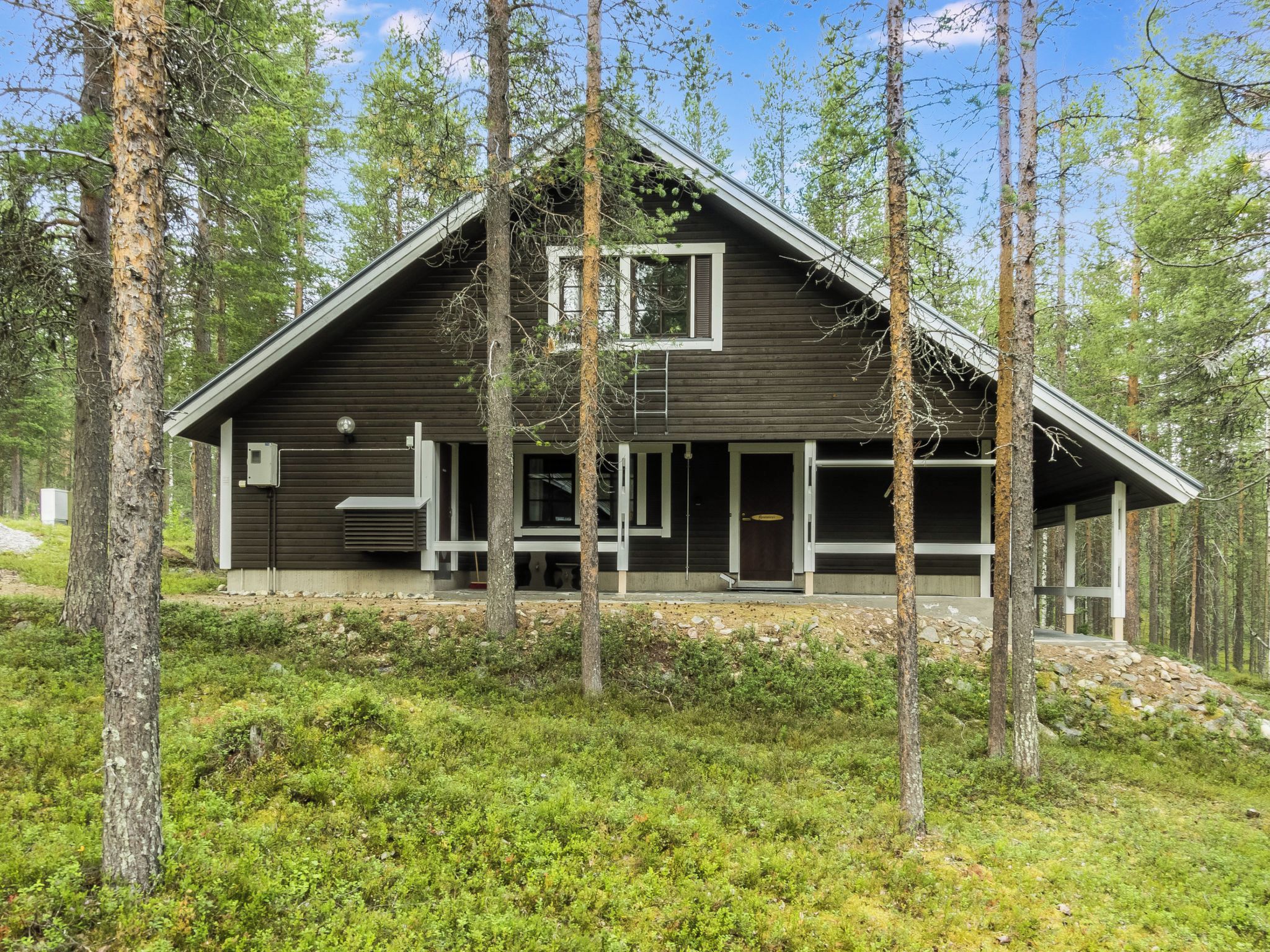 A modern cabin with a sloped roof, large windows, and a covered porch area.