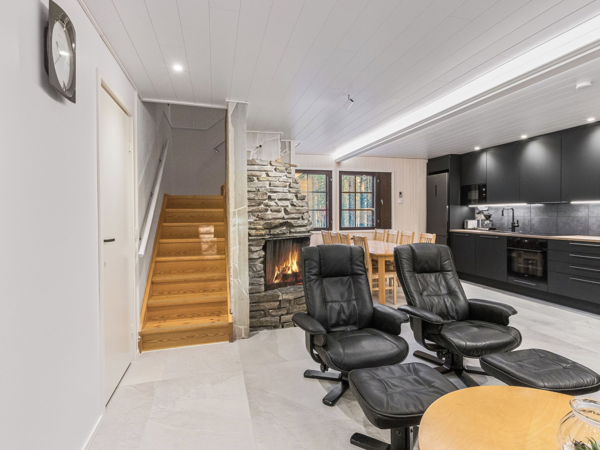 A modern kitchen with a black refrigerator, a built-in oven, and a coffee maker.