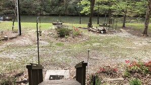 A wooden deck leading to a lake with a bench and a bird feeder. - Longrifle Lodge (Westminster)