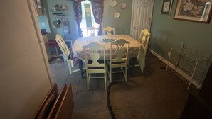 A dining area with a table and chairs, a chandelier, and a door. - Longrifle Lodge (Westminster)