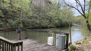 A wooden dock with a metal railing, a small sink, and a metal container. - Longrifle Lodge (Westminster)