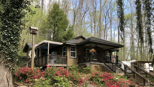 A cabin with a porch, a staircase, and a flower arrangement. - Longrifle Lodge (Westminster)