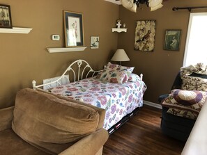 A bedroom with a bed, a chair, a lamp, and wall decorations. - Longrifle Lodge (Westminster)