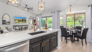 A modern kitchen with a large island, black cabinets, gold handles, and pendant lights. - LAKEFRONT!FREE HEATED POOL,SPA. BOAT, KAYAK. EV charger. Ocotillo Chandler.  (Chandler)