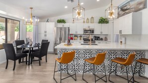 A modern kitchen with white cabinets, a central island, and bar stools. - LAKEFRONT!FREE HEATED POOL,SPA. BOAT, KAYAK. EV charger. Ocotillo Chandler.  (Chandler)