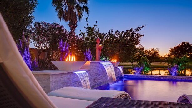 A poolside area with a waterfall feature, lounge chairs, and a statue. - LAKEFRONT!FREE HEATED POOL,SPA. BOAT, KAYAK. EV charger. Ocotillo Chandler.  (Chandler)