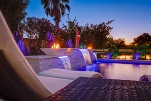 A poolside area with a waterfall feature, lounge chairs, and a statue. - LAKEFRONT!FREE HEATED POOL,SPA. BOAT, KAYAK. EV charger. Ocotillo Chandler.  (Chandler)