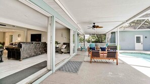 Un patio couvert avec une piscine, un canapé et un banc en bois.