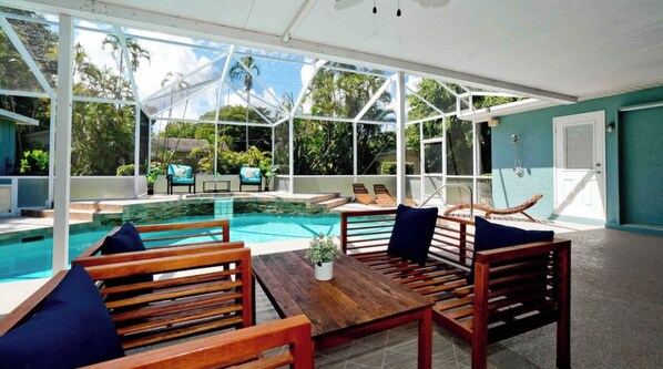 Un espace piscine extérieur abrité, doté de mobilier en bois et offrant une vue sur la végétation environnante.