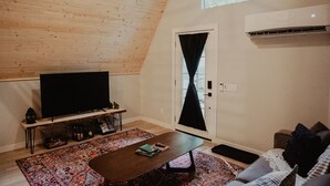 Un salon chaleureux avec un plafond en bois, un téléviseur à écran plat, une table basse et un canapé.