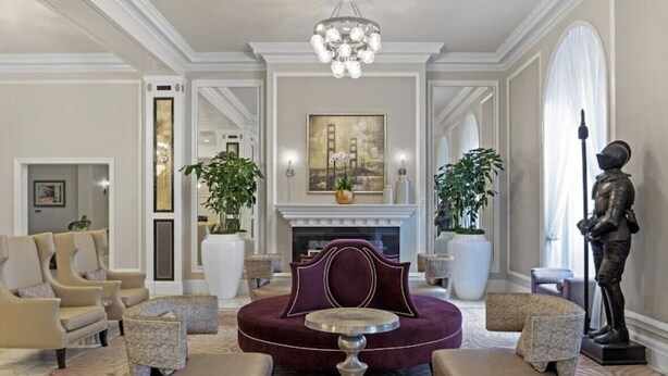 A luxurious living room with a fireplace, plush seating, and a statue.