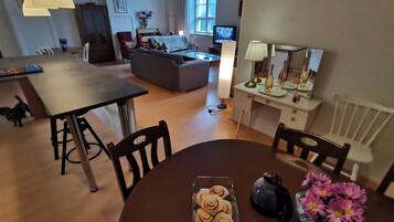 A cozy living room with a sofa, a dining table with chairs, a TV, and a lamp.