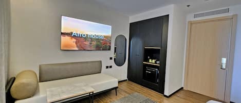 Una sala moderna con un sofá, un televisor de pantalla plana y un mueble de entretenimiento negro.